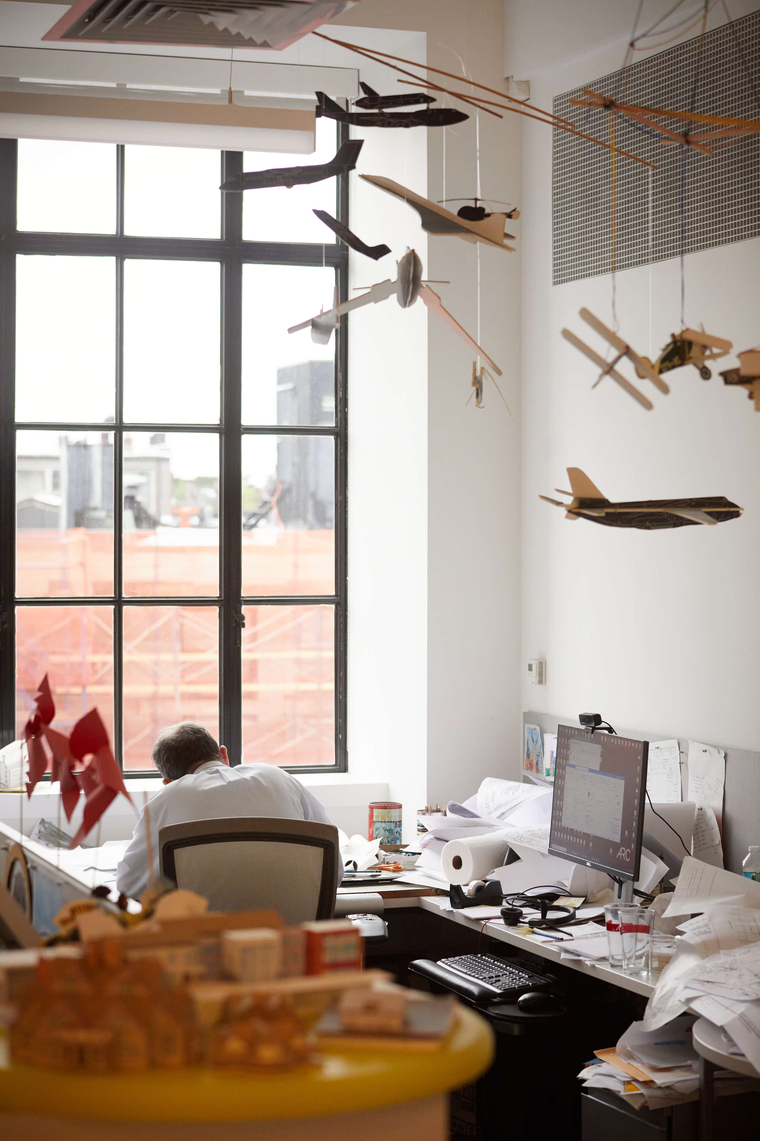 Model airplanes hang from ceiling above team members desk 